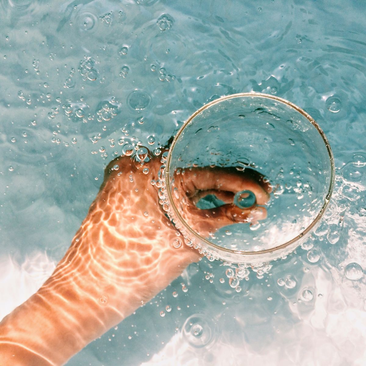 cropped hand of woman holding wineglass in swimming pool