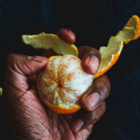 Cropped Hand Having Orange At Table