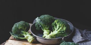 Close-Up Of Broccolis On Wooden Table Against Black Background