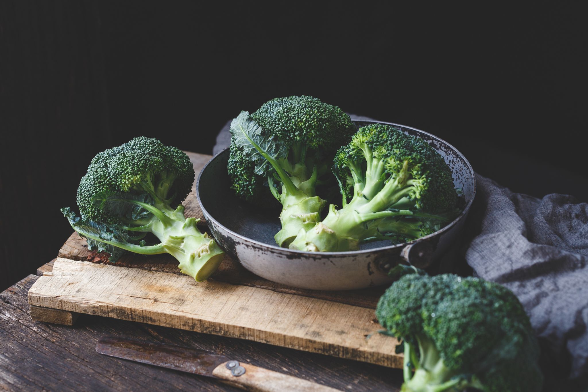 Close-Up Of Broccolis On Wooden Table Against Black Background