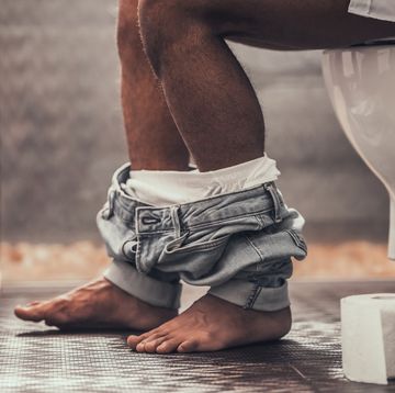 close up handsome young afro american man sitting on toilet in bathroom at morning personal morning routine fresh and relax at morning guy near mirror hygiene at morning concept