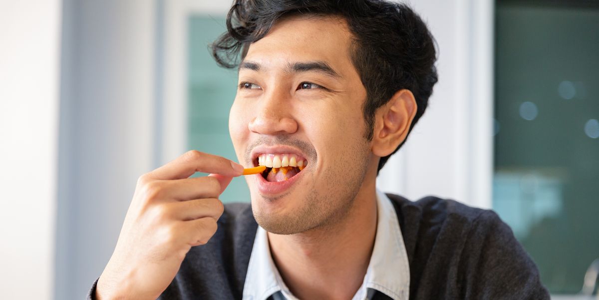 young college students adult male sat eating snack with happiness in room