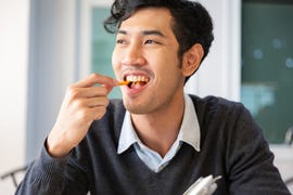 young college students adult male sat eating snack with happiness in room