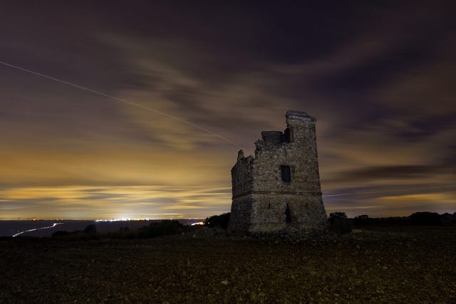 a stone building with a sunset in the background