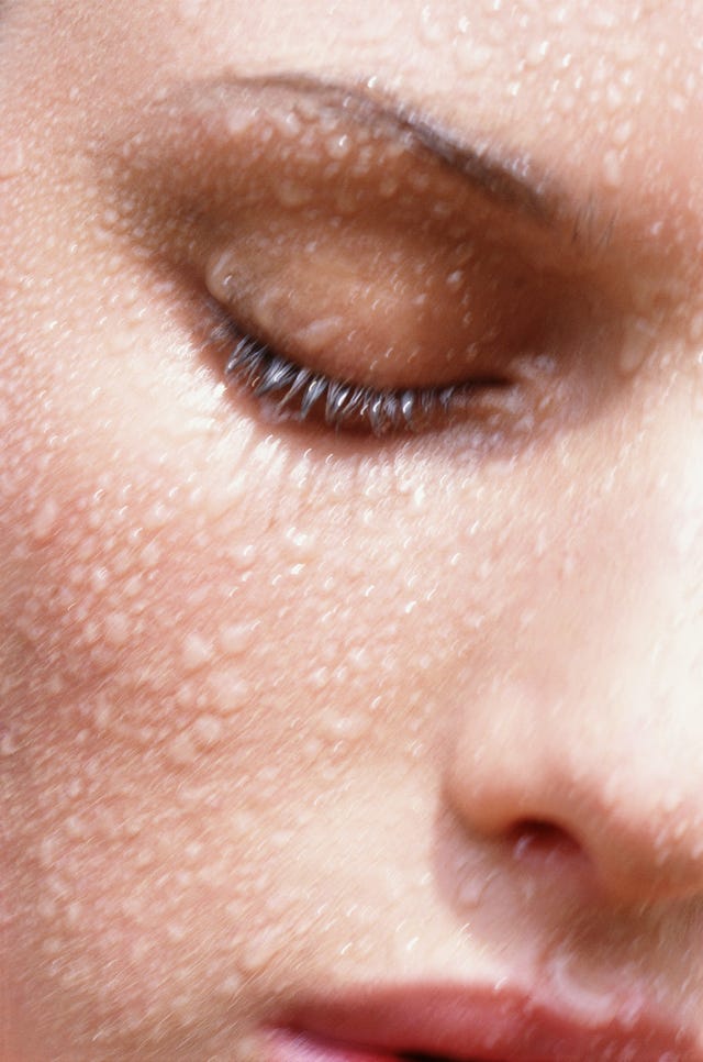 Gros plan d'un visage humide avec des gouttelettes soulignant la texture de la peau