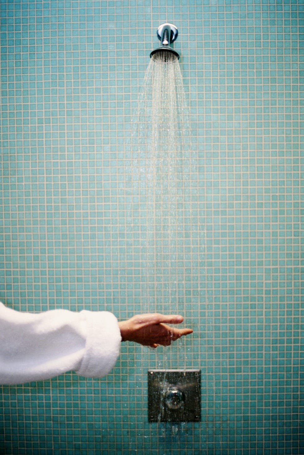 Woman testing shower with hand, close-up
