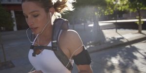 Woman jogging outdoors with backpack and earphones, close-up