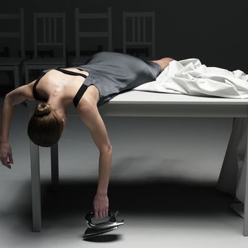 Woman lying on table with sheet holding iron
