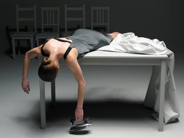 Woman lying on table with sheet holding iron