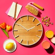 wooden clock with flowers cans notepad and lemon on a plate