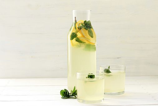 homemade lemonade in bottle, lemons on white wooden background made from lemon and mint
