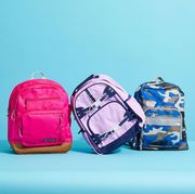 pink, blue and purple backpacks against a blue background to show good housekeeping's picks for the best kids backpacks