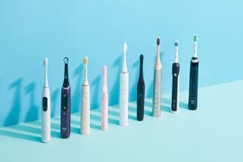 9 electric toothbrushes lined up next to each other on blue background