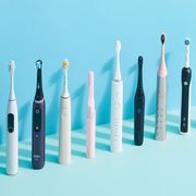 9 electric toothbrushes lined up next to each other on blue background