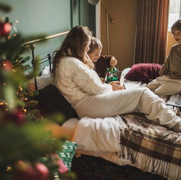 family with two children spend time together having fun and opening gifts during the christmas holidays in a decorated bedroom a mother with two sons siblings feeling excited opening presents in beautiful decorated bedroom