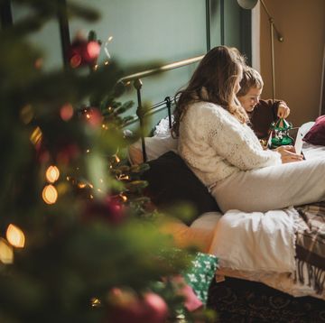 family with two children spend time together having fun and opening gifts during the christmas holidays in a decorated bedroom a mother with two sons siblings feeling excited opening presents in beautiful decorated bedroom