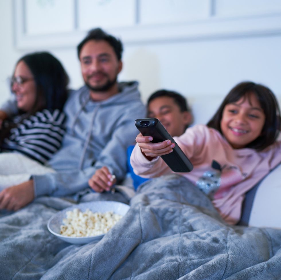 family relaxing on living room sofa and watching tv with popcorn at night