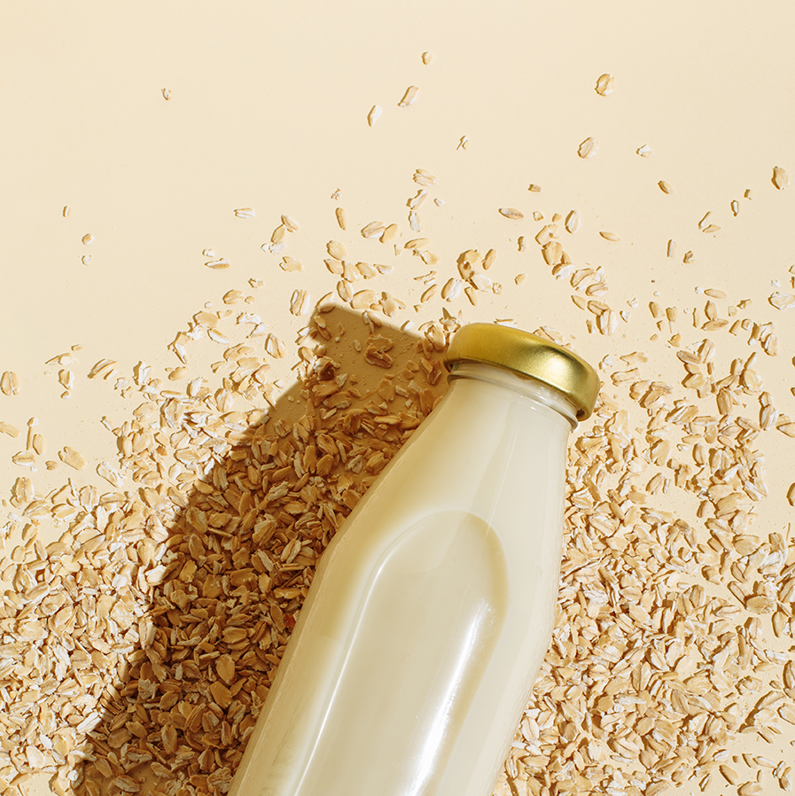 a bottle of oatmilk on top of scattered oats