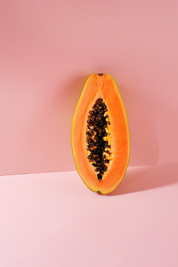 a piece of fruit cut in half on a pink background