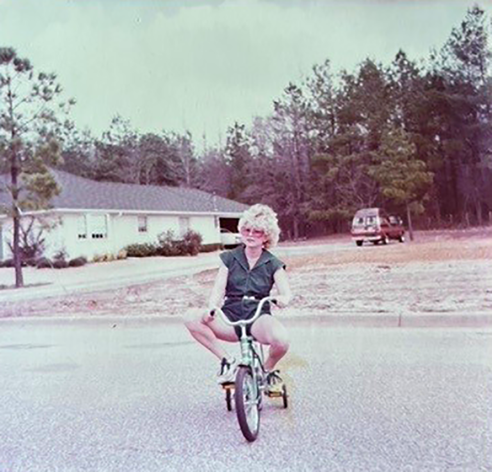 may cobbs mom riding on a small tricycle in the road wearing sunglasses and a green romper