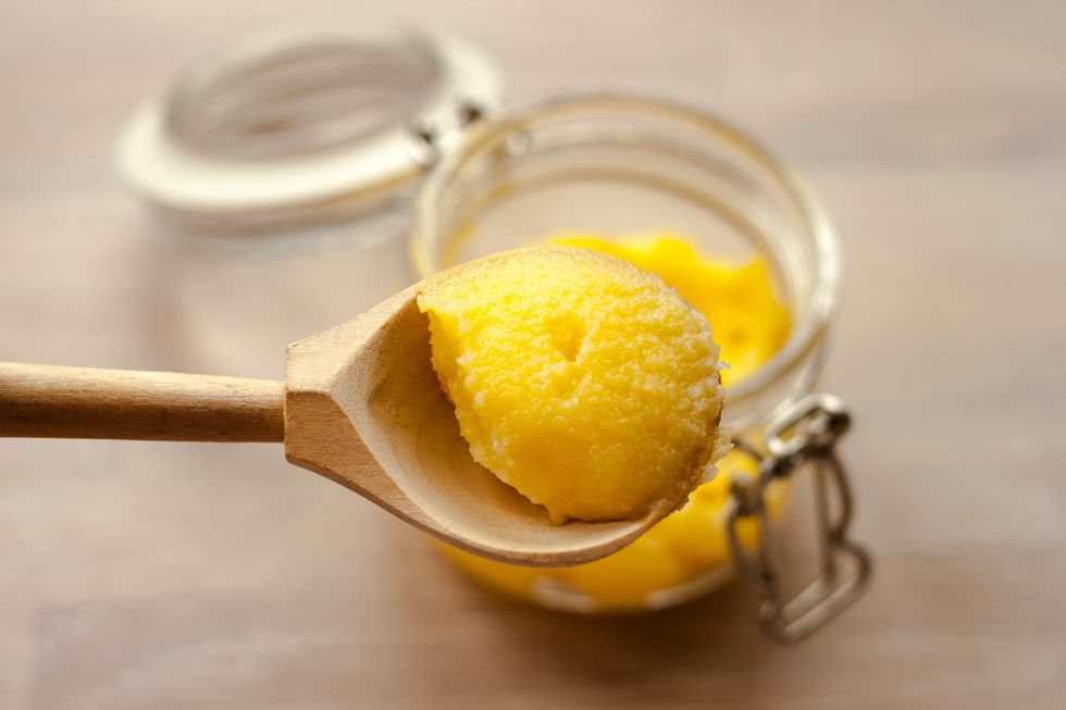 ghee clarified butter desi in glass jar with spoon made from wood on natural wooden background