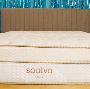 the saatva classic mattress on a bed frame in a photo set at good housekeeping