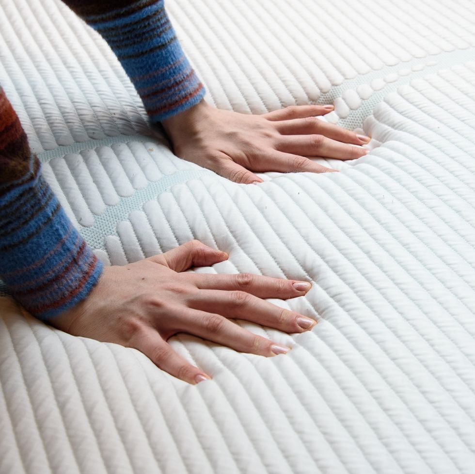 two hands pressing against a memory foam mattress