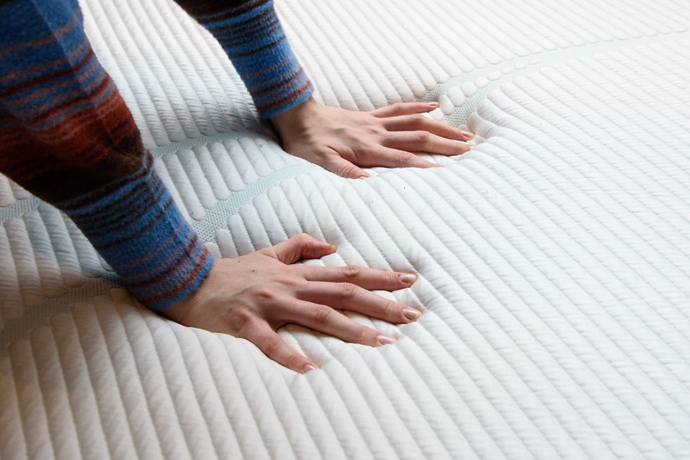 two hands pressing against a memory foam mattress