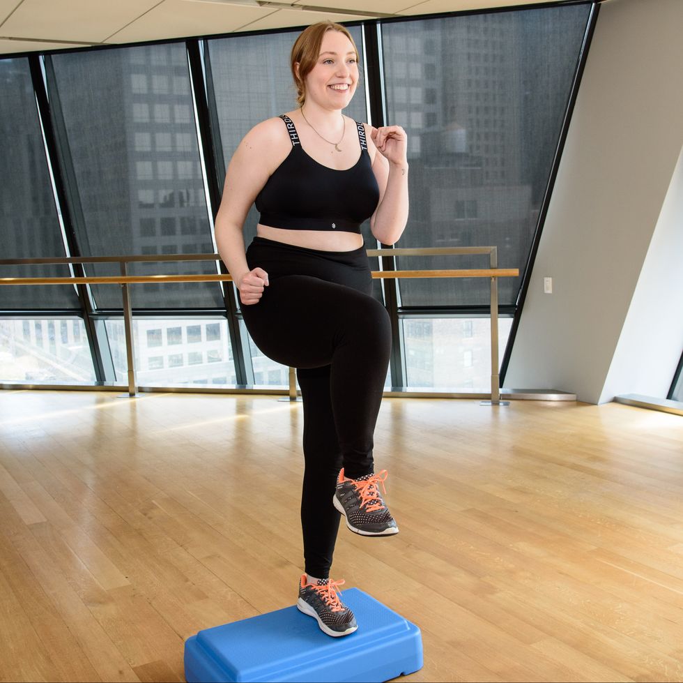 a woman exercising with a step up box in a black sports bra and black leggings, good housekeeping's testing for best sports bras