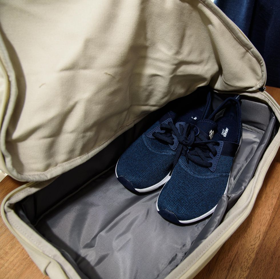a pair of navy sneakers inside of a lo and sons catalina deluxe bag as part of good housekeeping's best weekender bag testing