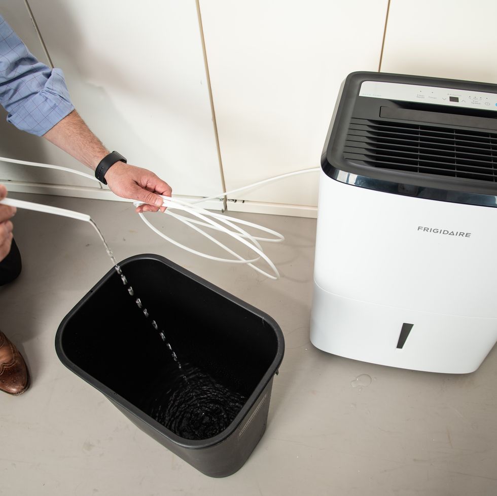 an expert tests the pump mechanism on a dehumidifier in the good housekeeping institute
