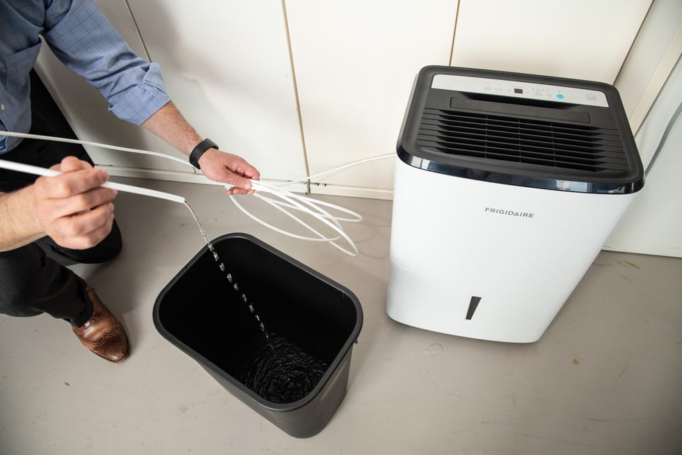 an expert tests the pump mechanism on a dehumidifier in the good housekeeping institute