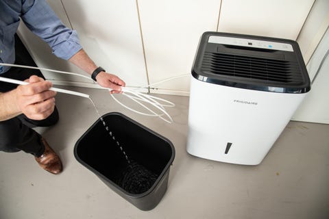 an expert tests the pump mechanism on a dehumidifier in the good housekeeping institute