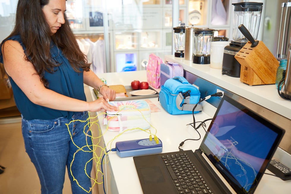 a kitchen expert using thermocouples to track the temperature of foods in an insulated kids' lunch box