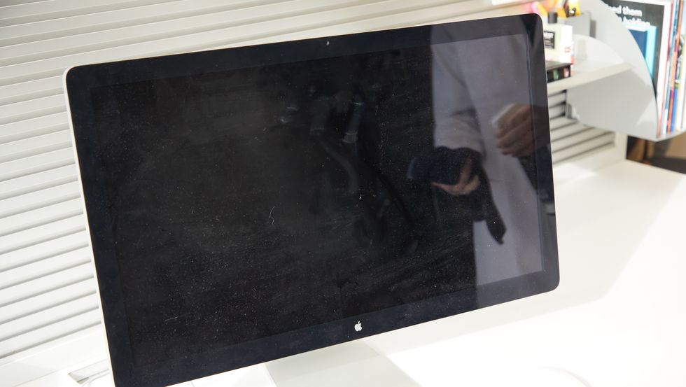 a computer monitor with a reflection of somebody spraying a screen cleaner on a cloth