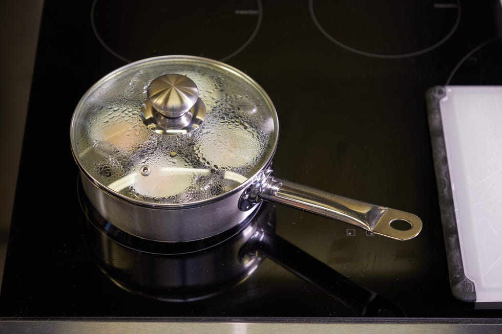 eggs cooking in an egg poaching pan with a steamy glass lid