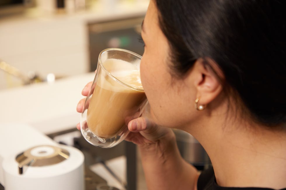 a person is drinking a latte in a kitchen setting