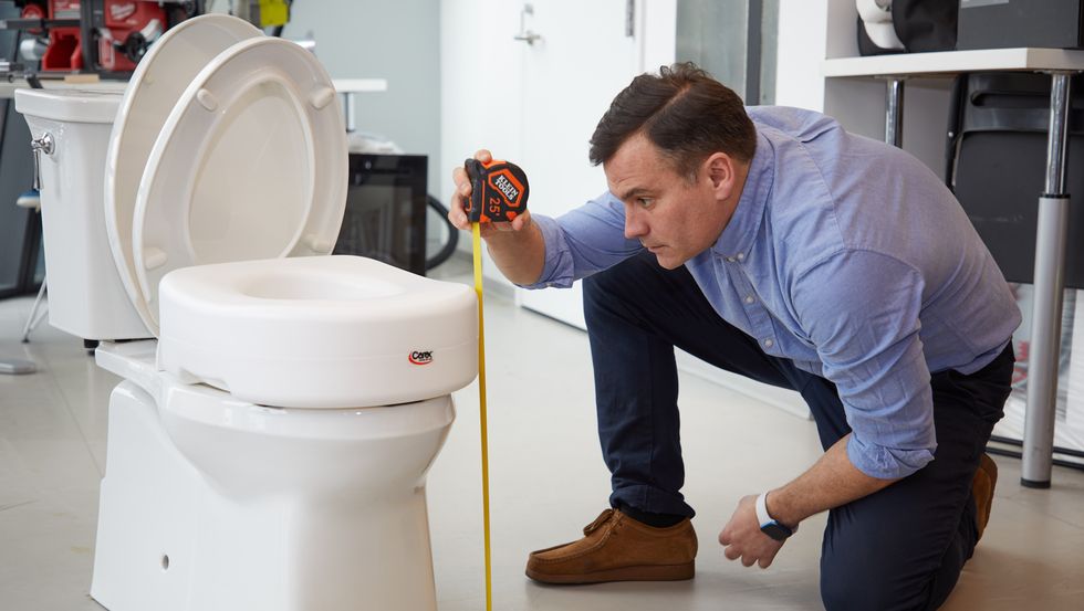 an expert measures the height of a toilet riser