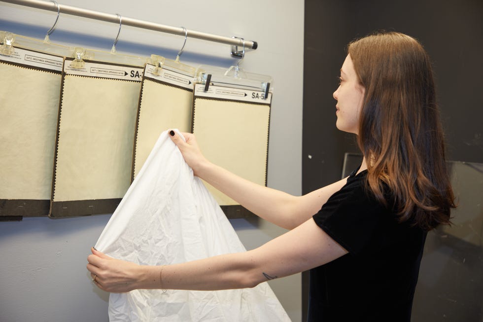 a person measuring wrinkle resistance of sheets against a visual guide from aatcc