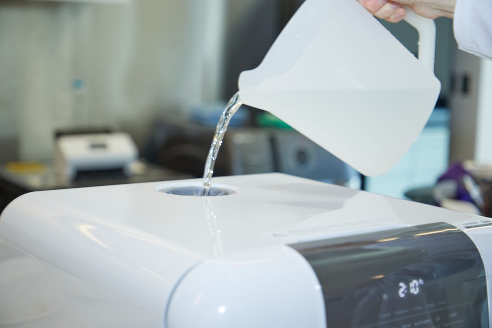 a pitcher of water being poured into the water tank of a portable dishwasher unit