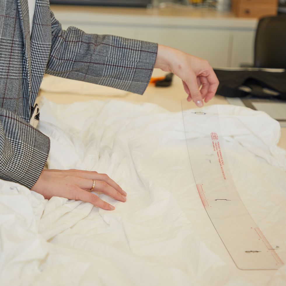 an analyst measures shrinkage markings on a sheet using a standardized lab measurement tool from aatcc