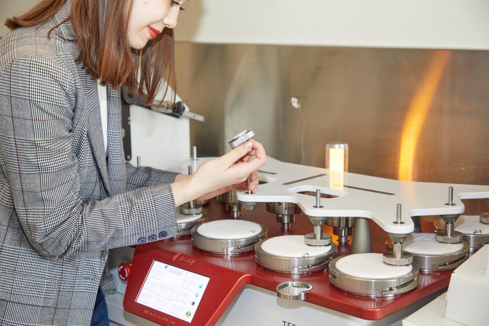 a textiles lab analyst inspecting a sheet swatch that has been tested for pilling using the martindale abrasion tester