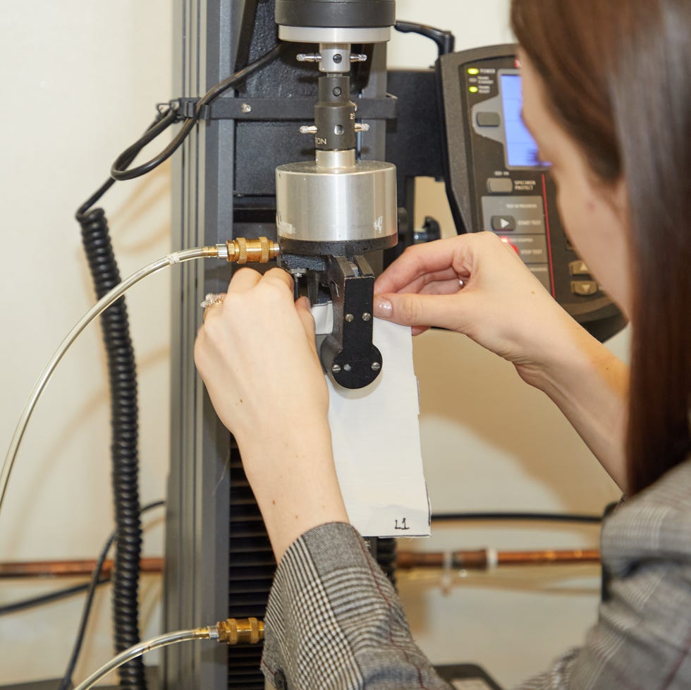 an analyst loads a fabric swatch into the clamps of our tensile strength testing machine