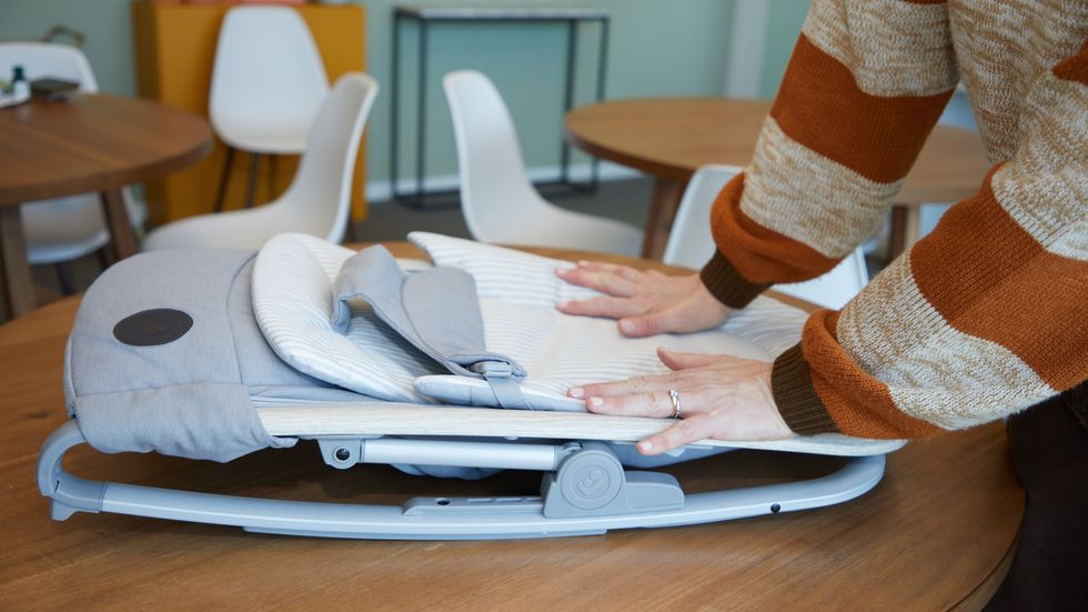 an expert at the good housekeeping institute testing the fold of a baby bouncer seat