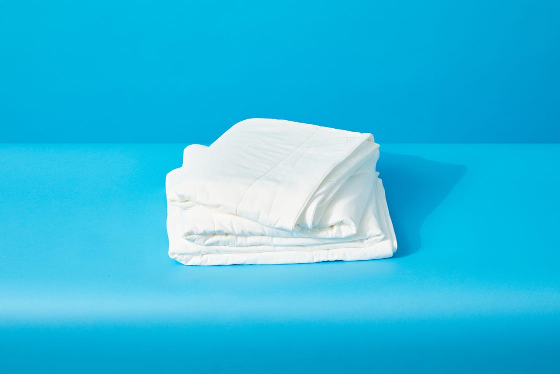 a white folded up cooling comforter from rest on a blue surface