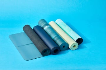 five rolled up yoga mats on a blue set, good housekeeping's best yoga mats