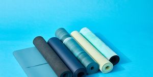five rolled up yoga mats on a blue set, good housekeeping's best yoga mats