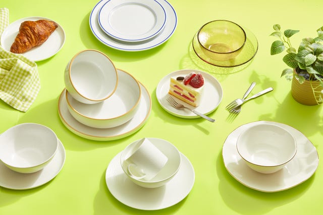 a green table with plates, bowls, a plant and food