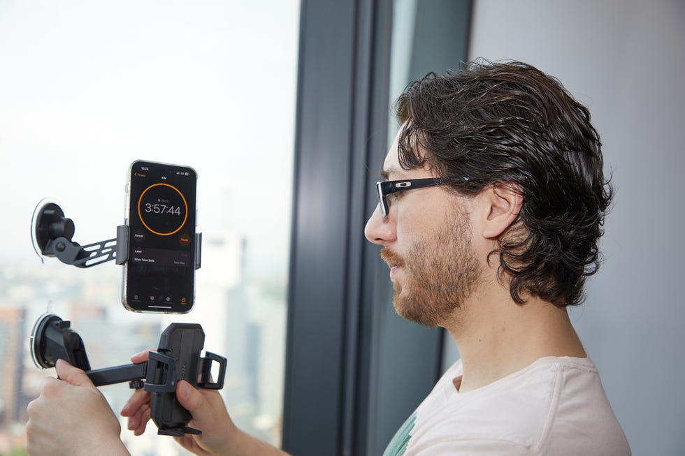 a man attaching car phone holder to windows to test suction efficacy
