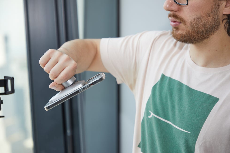 a man holding a phone using a magsafe car phone holder to test the strength of the magnet